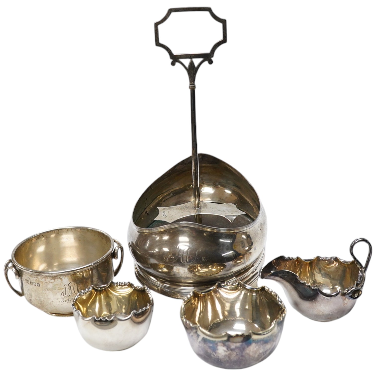 A George III silver oval cruet stand, London, 1804, (lacking bottles), height 28.7cm, together with two silver bowls, one two handled by Mappin & Webb, London, 1911 and a plated bowl and jug. Condition - poor to fair.